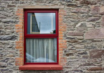 Close up view of a red window on a brownish gray color European brick wall background
