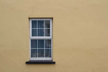 Close up view of a white window on a yellow or tan color European building cement wall background