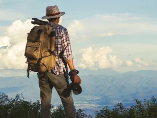 Tuinposter male traveler photographer fascinated by illuminated nature mountains at morning time. © AungMyo