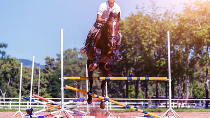 Young sportsman taking his course on show jumping competition; The horse jumps over the barricade; Equestrian Sports,  Horse Riding