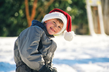 Portrait of a boy on a winter walk . Funny boy in Santa hat .