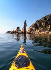 The bow of the sea kayak on the background of the rocky sea coast.