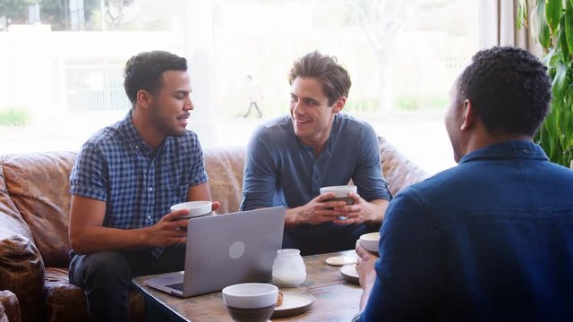 Young adult men drinking coffee and talking at a coffee shop