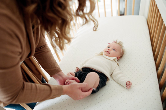 Mother Holds Baby Feet In Crib