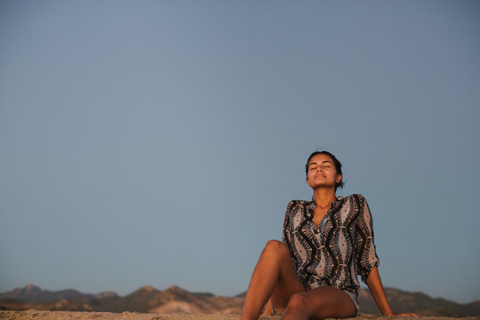 Content young woman spending time alone on the beach at sunset