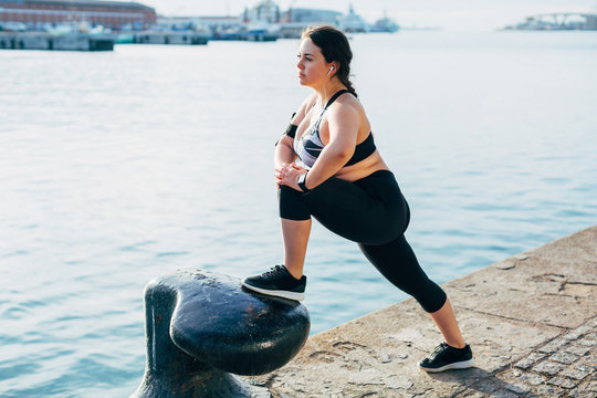 Plus size woman doing stretching exercises at seaside.