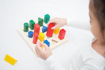 Portrait of asian little cute girl playing colorful blocks in different shapes on white background. Learning by playing brain training education home school concept.