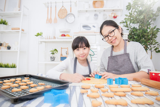Portrait Of Little Asian Girl And Her Mother Baking Cake And Cookies In The Kitchen. Happy Asian Family And Mother’s Day Concept