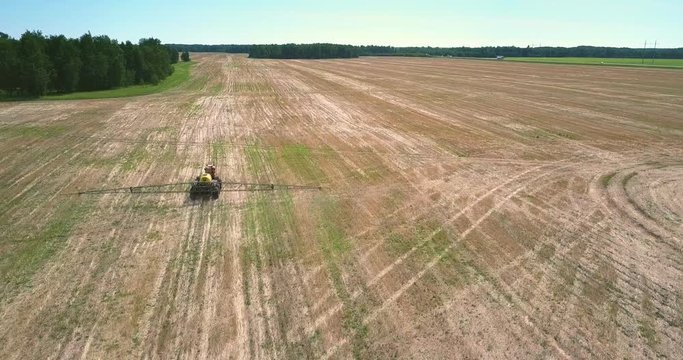 fertilizer spreader with long bars drives along harvested field