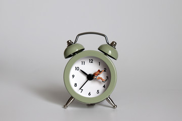 A miniature woman hanging from the hands of a watch.