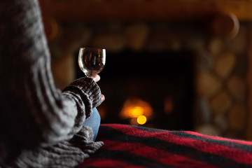 sitting in cozy cabin by fieldstone fireplace with glass of wine