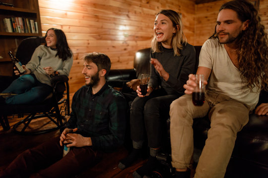 A group of friends laugh and drink together in a cabin in upstate New York