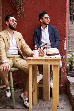 Two relaxed stylish friends at an outdoor bar