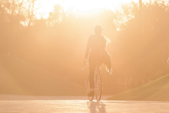 Male's silhouette riding vintage bicycle in the golden hour