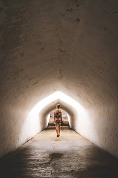 A young woman walking through a tunnel in an ancient palace