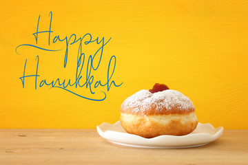 Image of jewish holiday Hanukkah with traditional doughnut on the table.