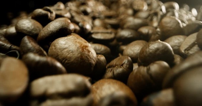 Super macro slide shot of a pile of coffee beans on a black background. 
