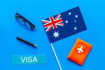 Visa to Australia concept. Text visa near passport cover and australian flag on blue background top view