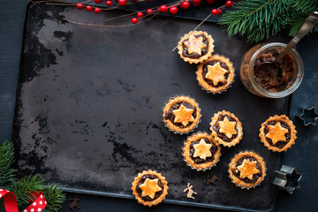 Freshly baked mince pies - Traditional Christmas fruit tarts - on a vintage baking tray with festive Xmas decorations