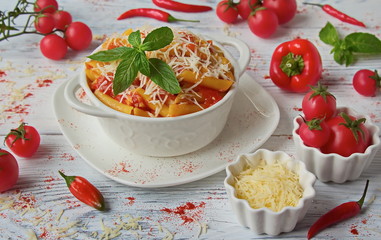 Penne pasta with Arrabiata sauce in a white dish on a white table. Fresh cherry tomatoes, chili...