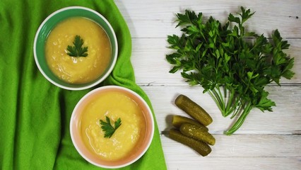 Delicious pea puree soup on green napkin and wooden background.