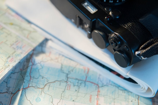Camera and notebook on top of maps