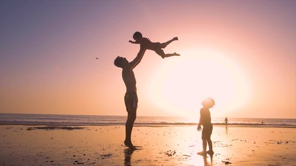 Ultra slow motion - silhouette of father and son playing together in the beach at sunset