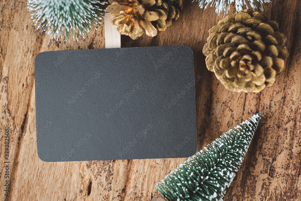 Poster top view of blank blackboard with xmas tree and gold pine cone on grunge wood table .winter holiday 