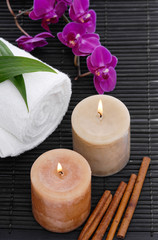 Obraz na płótnie Canvas Spa setting with candle, towel ,orchidin bowl, cinnamon on mat