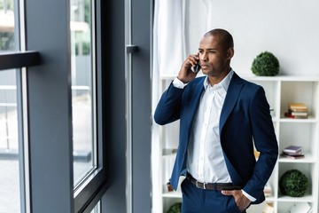 handsome african american businessman talking on mobile phone in modern office.
