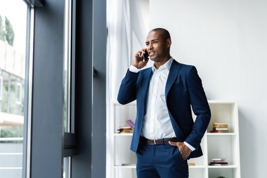 handsome african american businessman talking on mobile phone in modern office.