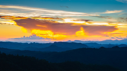 Landscape scene of colorfull sunset sky with mountain range and forest.