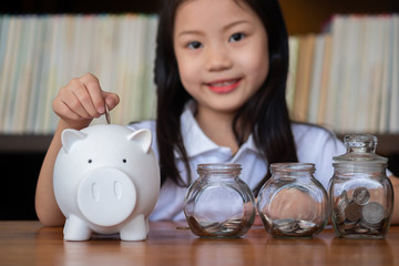 cute girl putting money coins in piggy bank,saving money concept