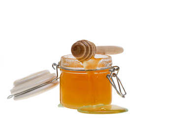 glass jar full of honey and dipper isolated on white background