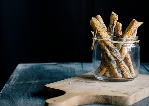 Breadsticks in jar on wooden cutting board