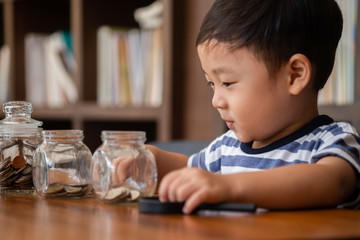 cute boy putting money coins in glass,saving money concept