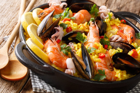 Spanish traditional cuisine: hot paella with seafood shrimps, mussels, fish, and baby octopuses close-up in a frying pan. horizontal