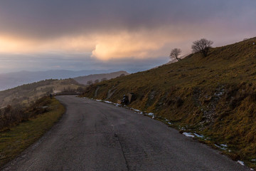 Mountain road with mist filling a valley in the background and warm sunset colors