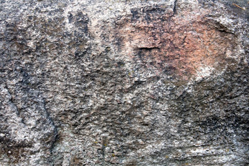Uneven surface of big grey granite boulder with pink inclusion, may be used as background or texture