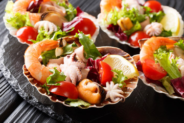 Fresh seafood salad with vegetables and lemon served in seashells close-up. horizontal