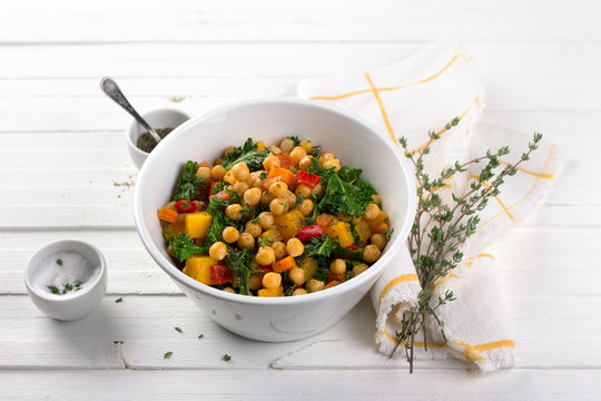 Homemade ragout with pumpkin, carrots, sweet peppers, tomatoes, chickpeas, kale and thyme in a white bowl on a white background. delicious healthy food