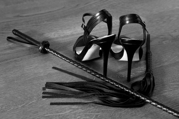 high heels sandals in shiny black leather with small platform sole and ankle strap. black high heels and sex toys. Sexy woman fetish pumps and whip, bdsm concept. - obrazy, fototapety, plakaty
