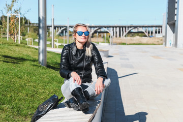 Obraz premium The woman sits on a bench in jeans, a jacket
