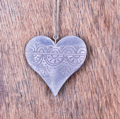 steel shaped heart hanging by a string on wooden background