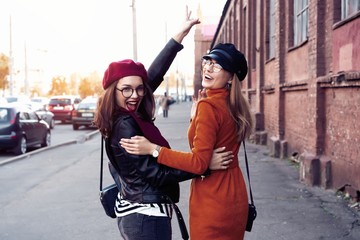 Outdoors fashion portrait young pretty best girls friends in friendly hug. Walking at the city....