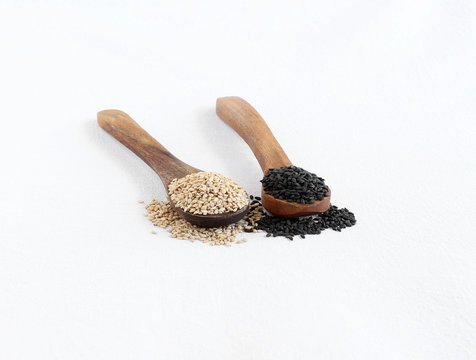 Healthy food white and black sesame seeds, rich in essential nutrients and high oil content, on wooden spoons.