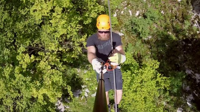 Man with beard canopying over the forest on zipline in Slovenia.