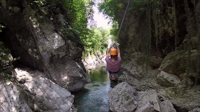 Man heading through river canyon on zipline in Slovenia.