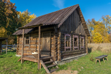 Old house of logs in the Russian village. Bench in the yard.