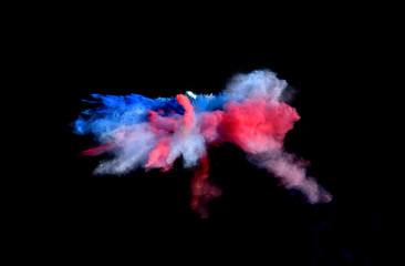 Multi Colored forms of powder paint and flour combined  together explode in front of a black...